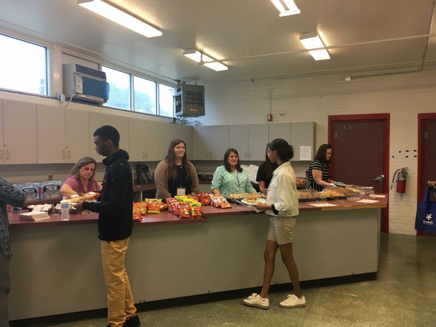 A group of people are standing around a counter in a kitchen.