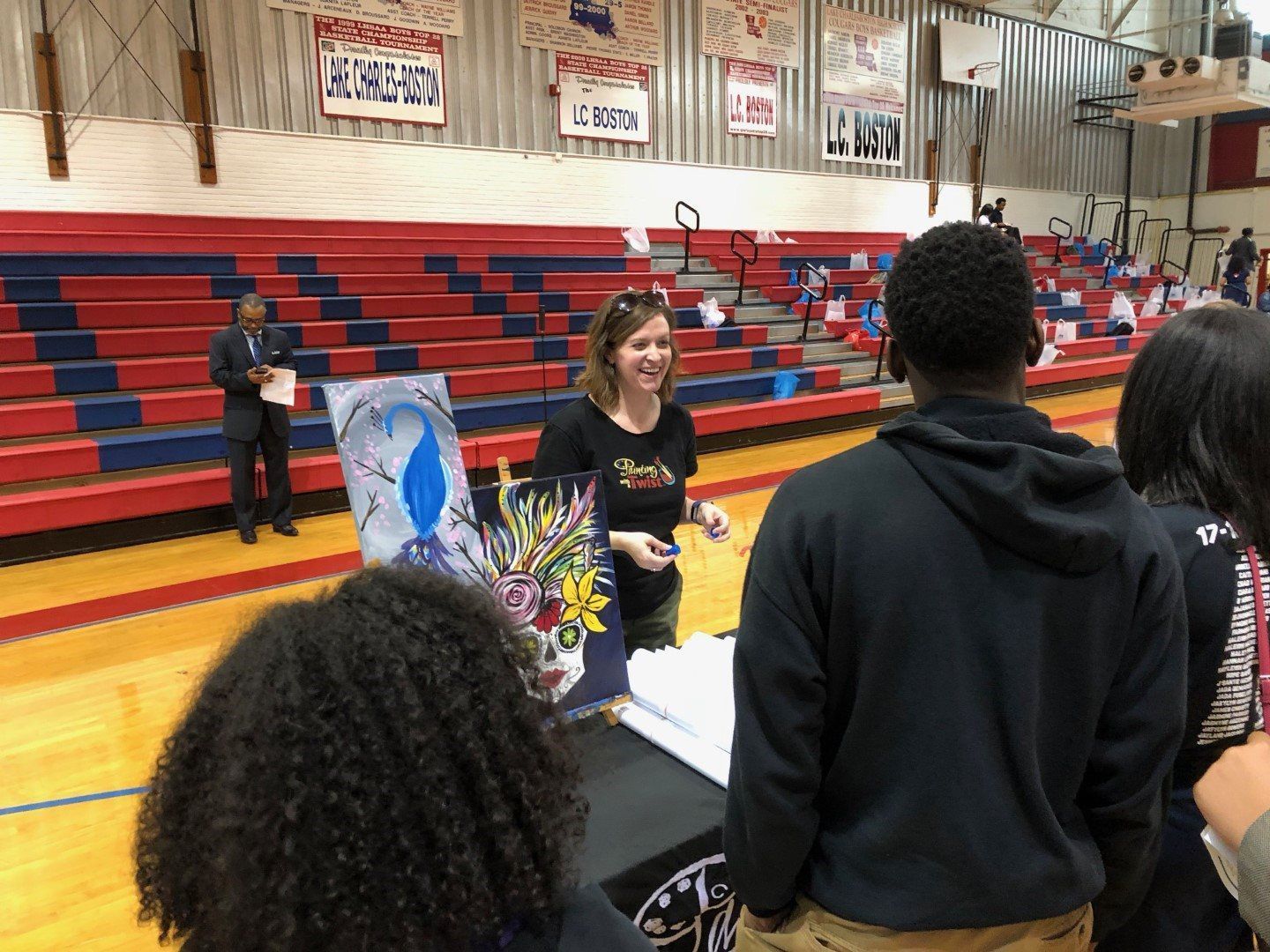 A woman is talking to a group of people in a gym.