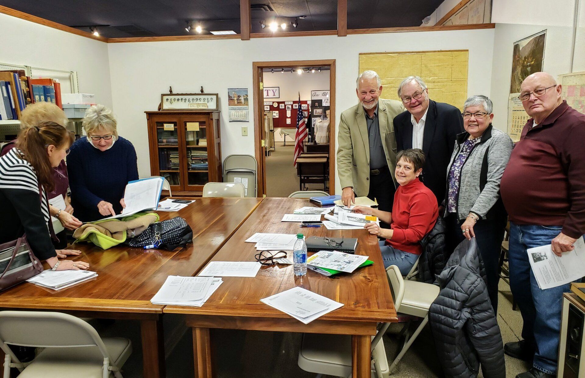 Group of people at a long table reviewing documents. They are in a room with exhibits.