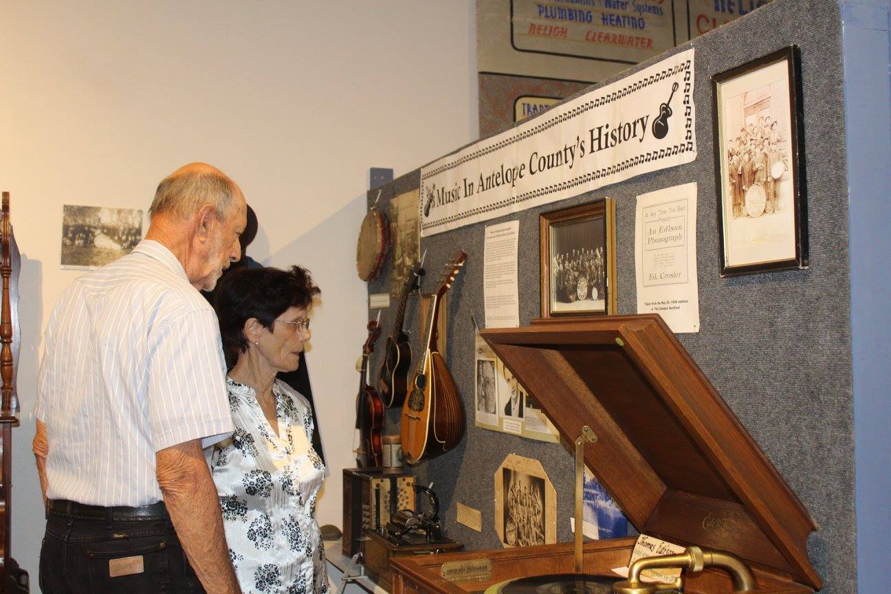 Two people viewing a display of historical items, including a phonograph and musical instruments.