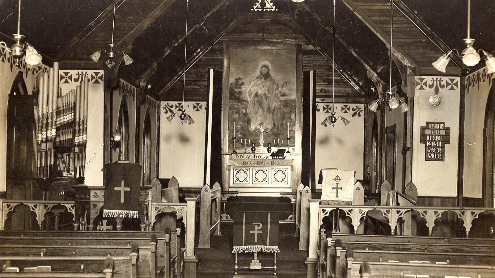 Interior of a church with rows of pews, altar, and a large painting of Jesus.