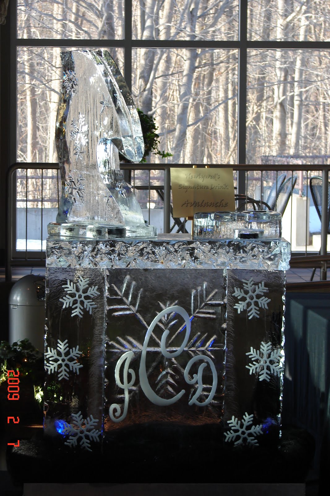 A large ice sculpture with a monogram on it is sitting in front of a window.