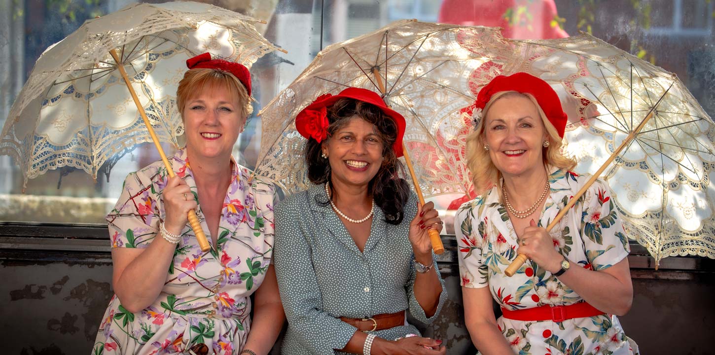 Three women with umbrellas on a bench