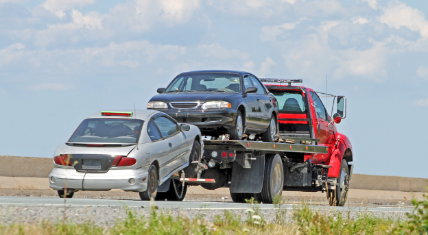 Car carrier truck loaded with three cars on a road under a blue sky