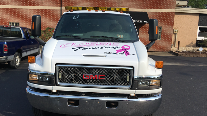 White GMC truck parked in front of a brick building, viewed from the front.