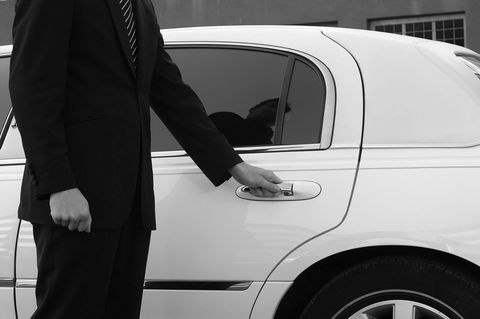 Chauffeur helping a bride out of a wedding limo on Long Island, NY