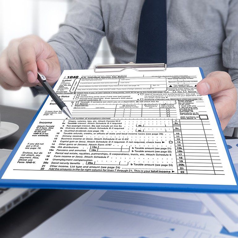 Business Man Holding A Tax Form — Hot Springs, AR — Malone Tax & Bookkeeping Business Man Holding A Tax Form — Hot Springs, AR — Malone Tax & Bookkeeping