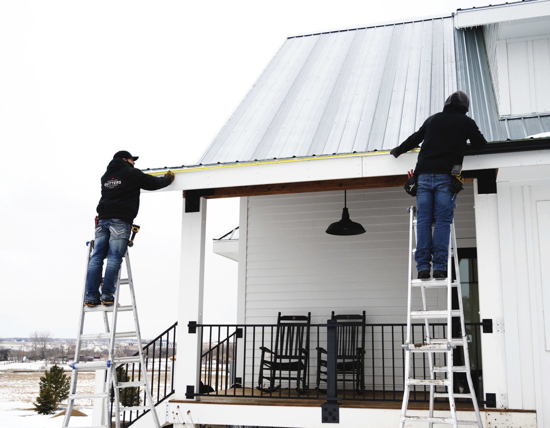 two men are working on the roof of a white house