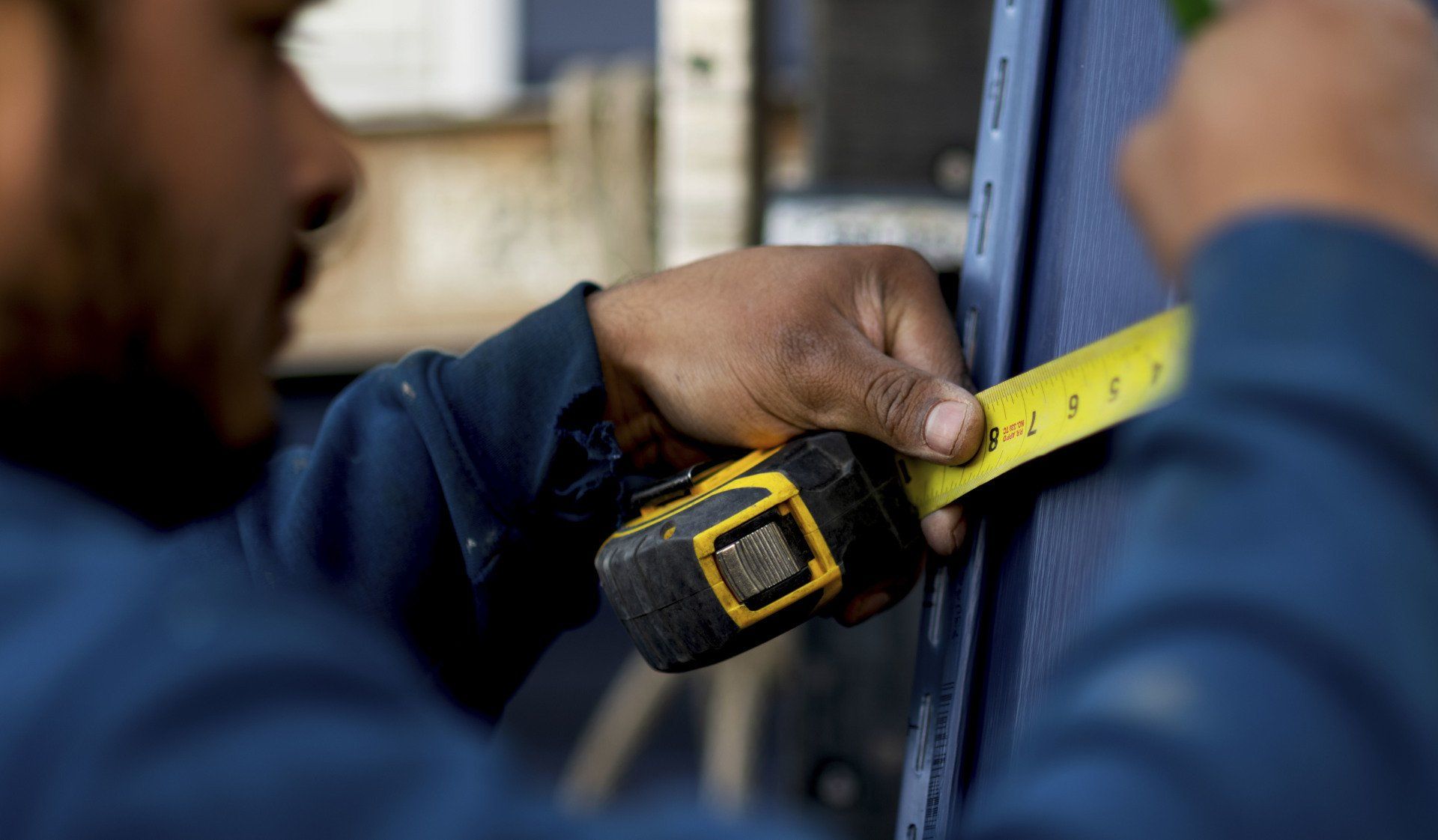 a man is measuring a piece of metal with a tape measure .