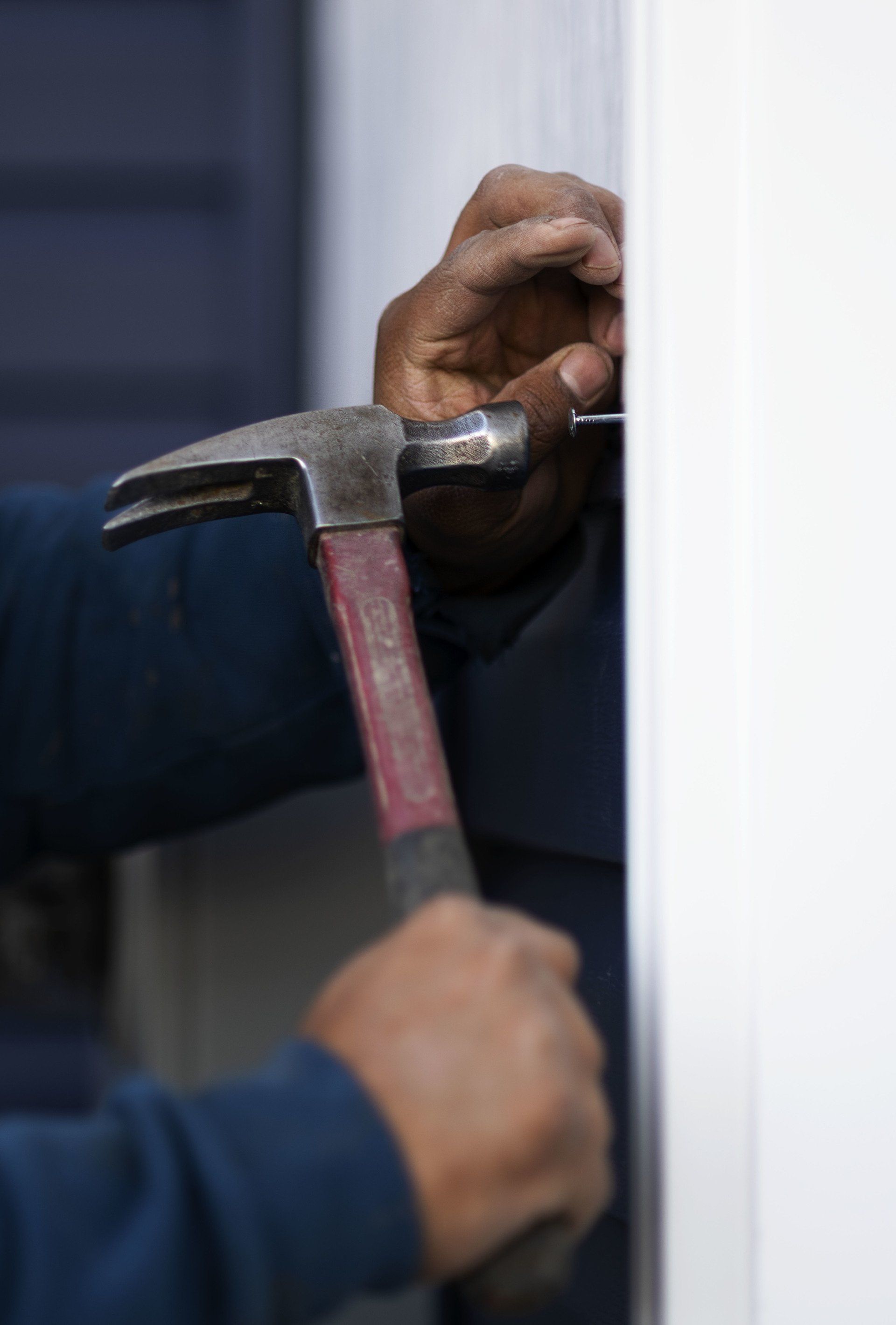 a man is using a hammer to hammer a nail into a door .