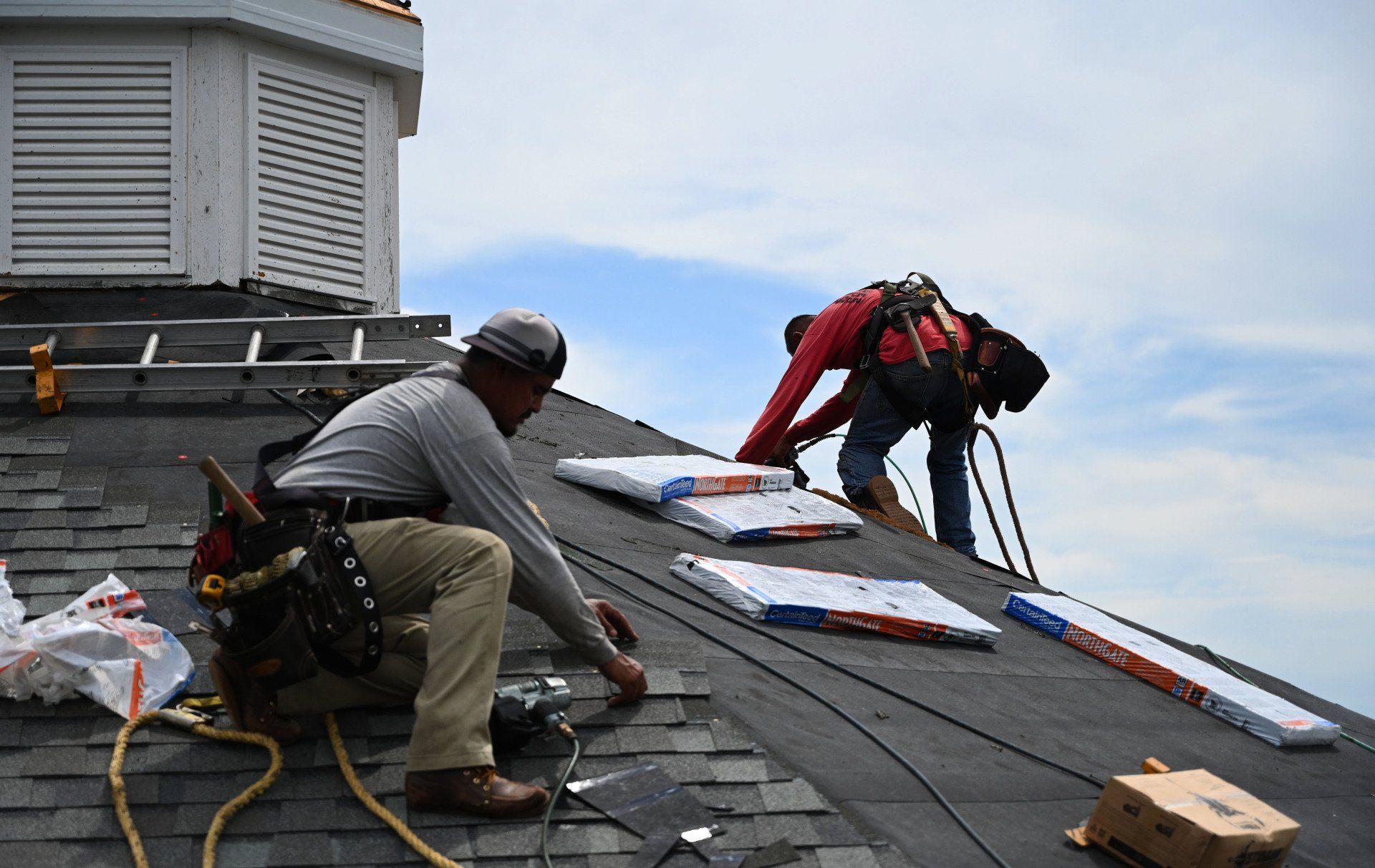 two men are working on the roof of a building .