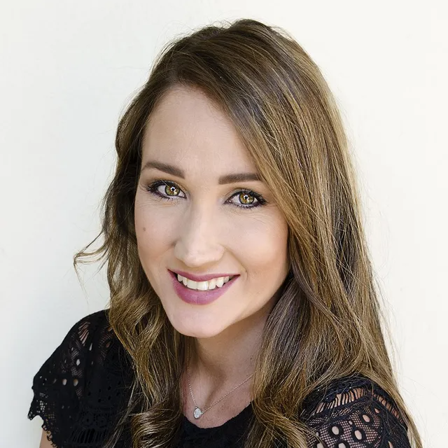 Smiling woman with long brown hair against a light background