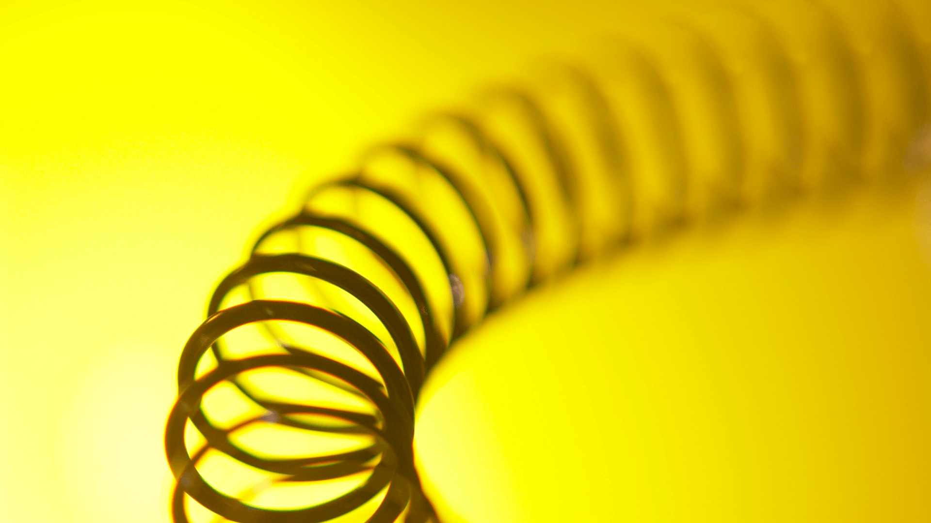 Black metal spring coil on a bright yellow background
