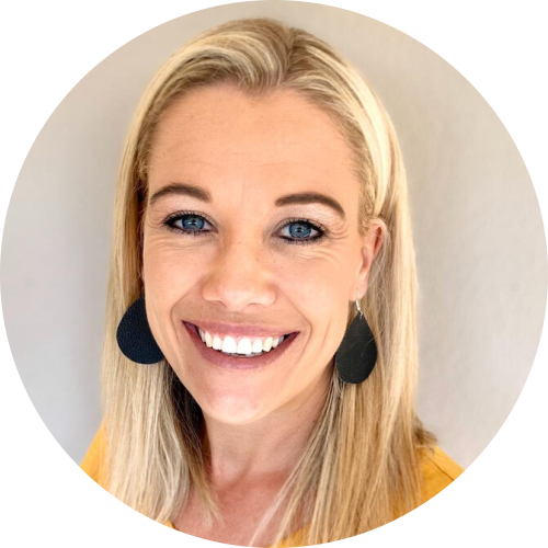 Smiling blonde person in black earrings and yellow top against a light background
