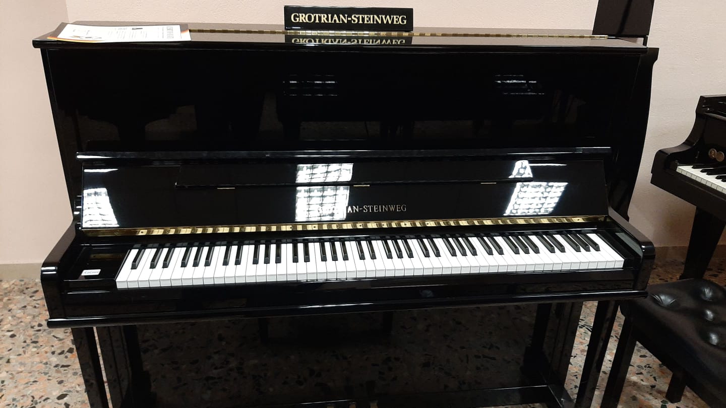 Un pianoforte nero con un cartello in cima che dice 