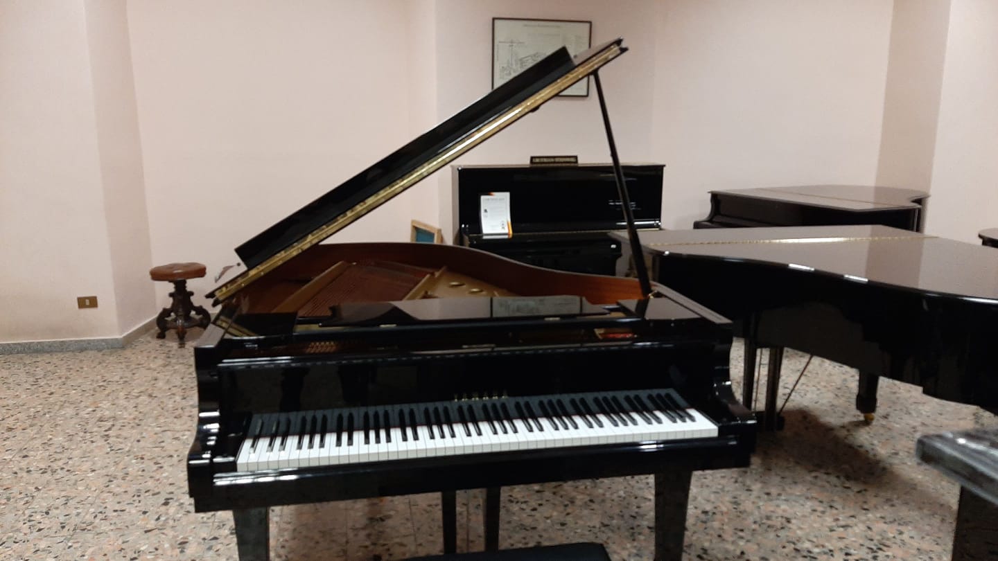 Un pianoforte è seduto in una stanza con altri pianoforti