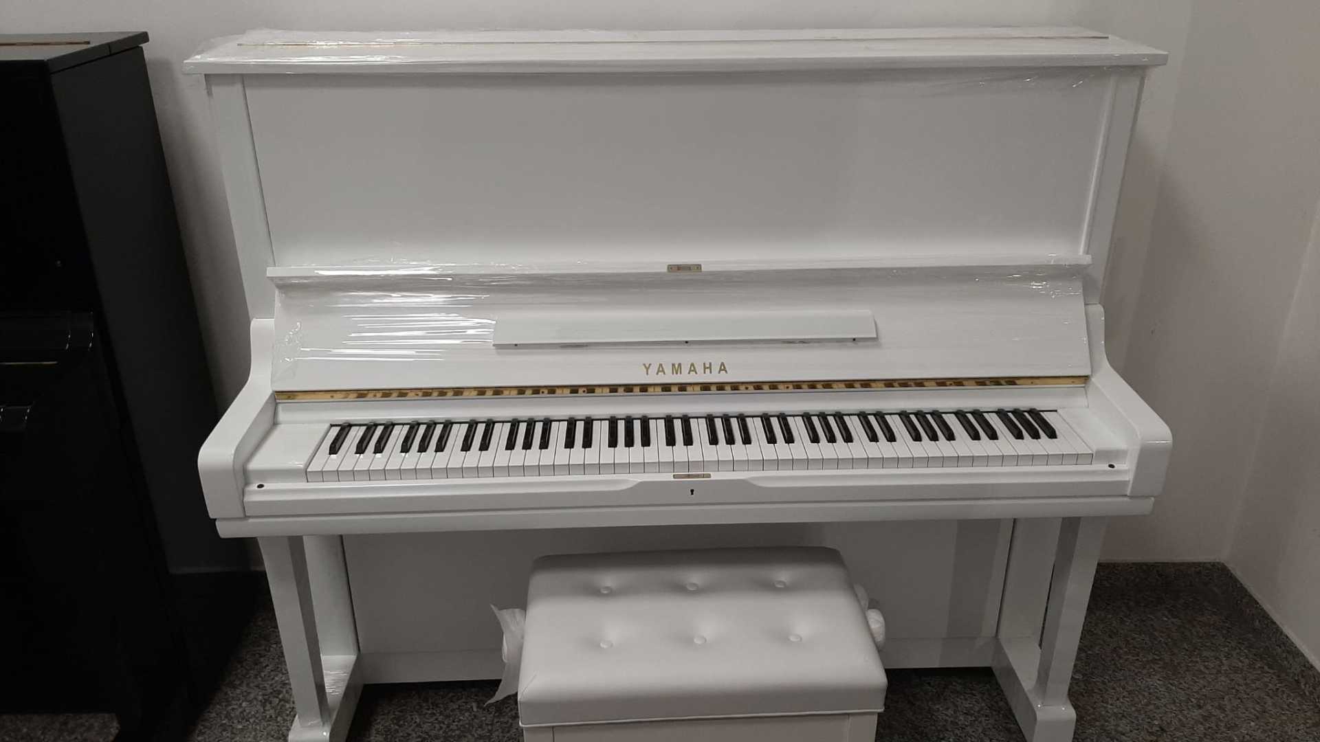 Un pianoforte bianco è posizionato in una stanza accanto a un pianoforte nero.