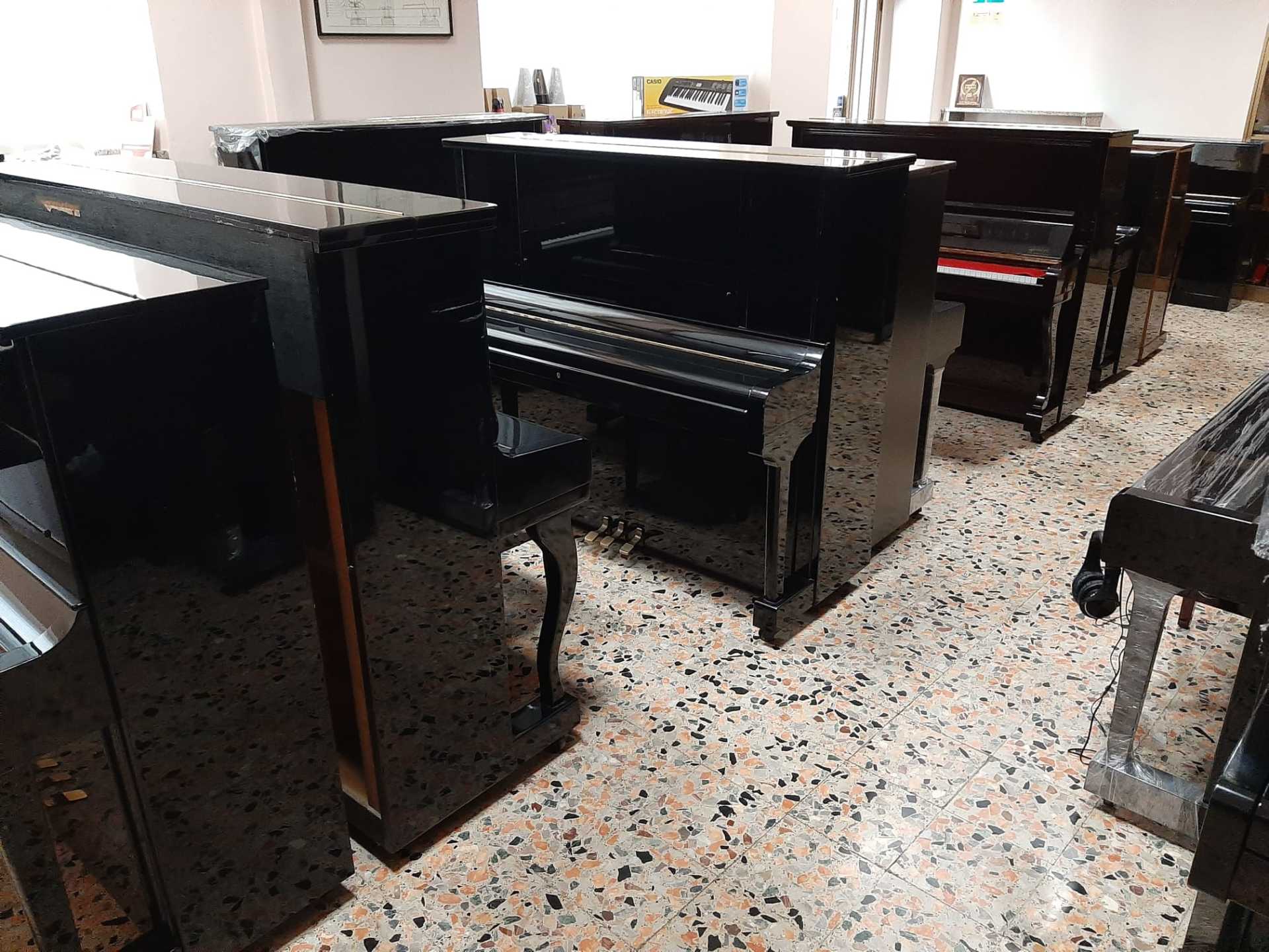 Una fila di pianoforti neri sono allineati in una stanza