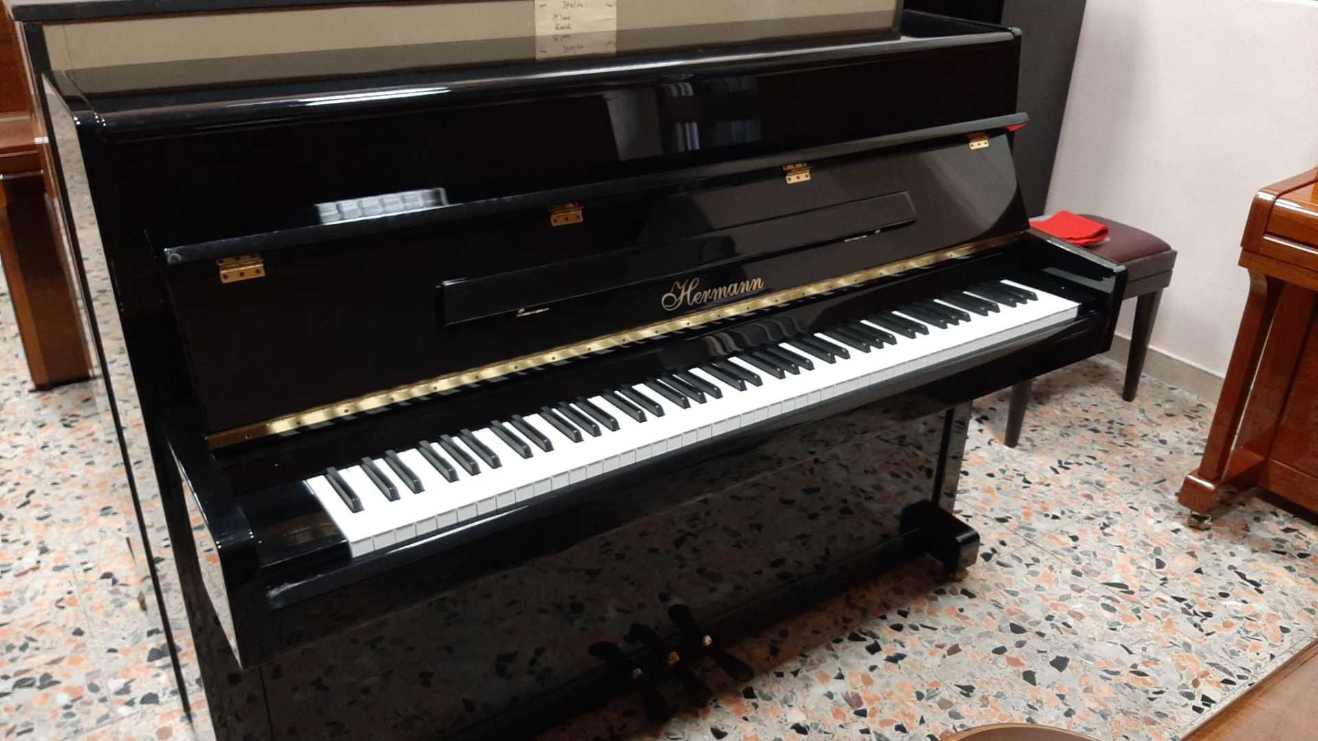 Un pianoforte nero è appoggiato su un pavimento piastrellato