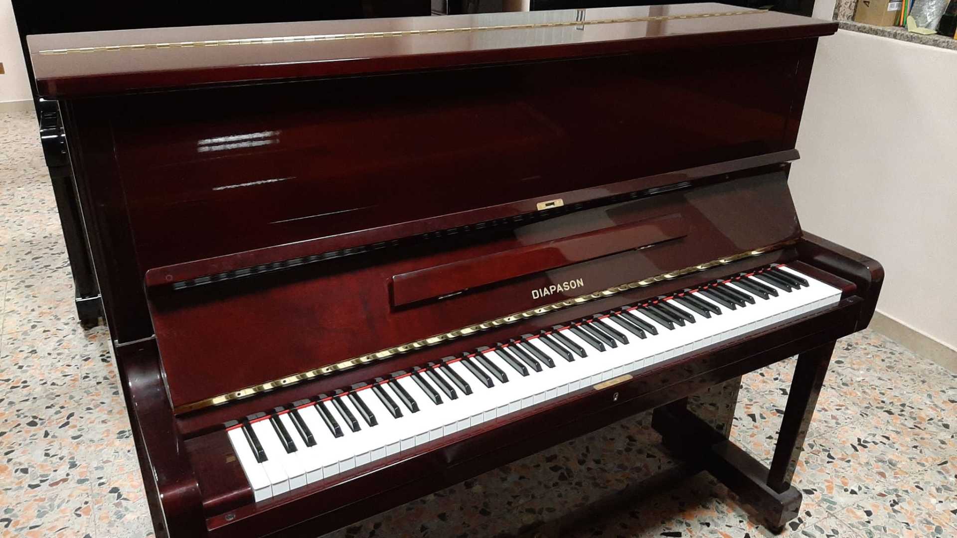 Un pianoforte è appoggiato su un pavimento piastrellato in una stanza