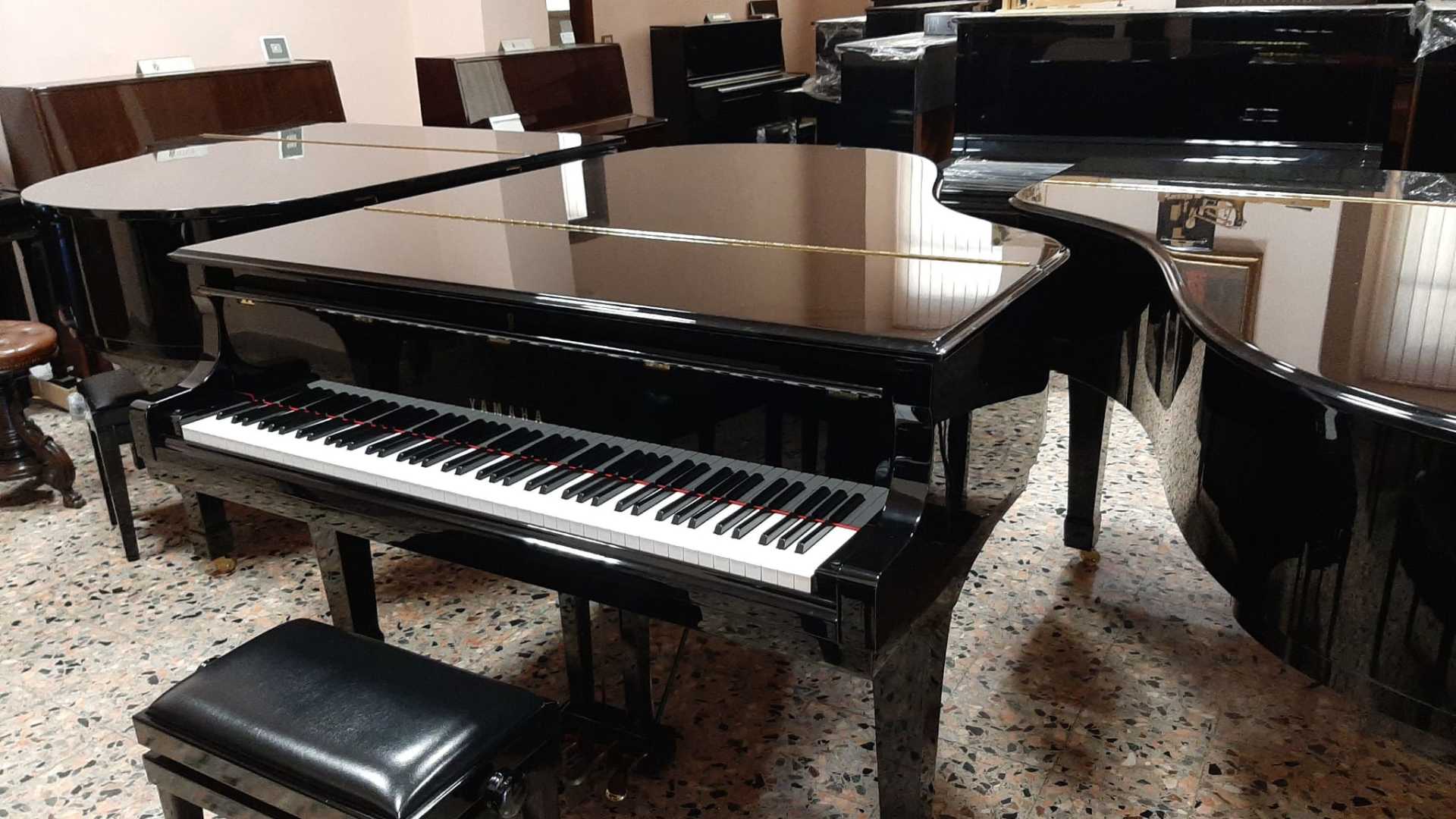 Un pianoforte a coda nero si trova in una stanza con altri pianoforti