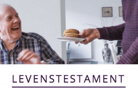 Iemand serveert een bord koekjes aan een lachend persoon in een informele huiselijke setting, met daaronder de tekst LEVENSTESTAMENT.