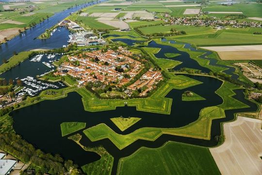 Luchtfoto van de stervormige vestingstad Willemstad in Nederland, omgeven door een gracht, velden en een rivier.