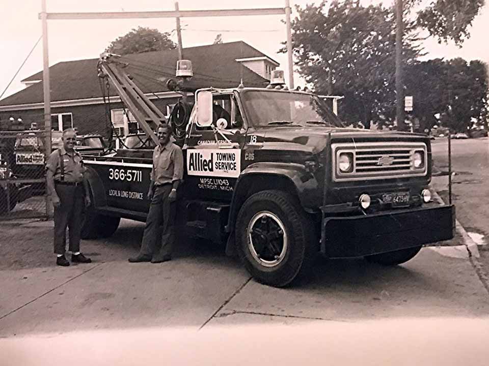 Recovery Specialists — Employee Standing Next to Company Towing Truck in Detroit, MI