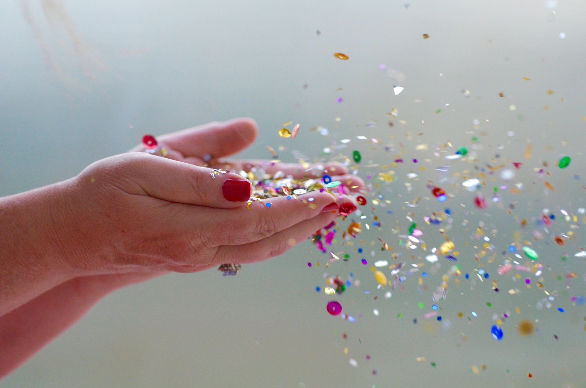 Hands catching colorful confetti against a light background