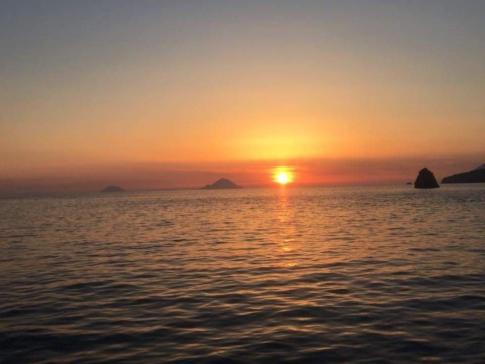 Il sole sta tramontando sull'oceano con alcune isole in lontananza.