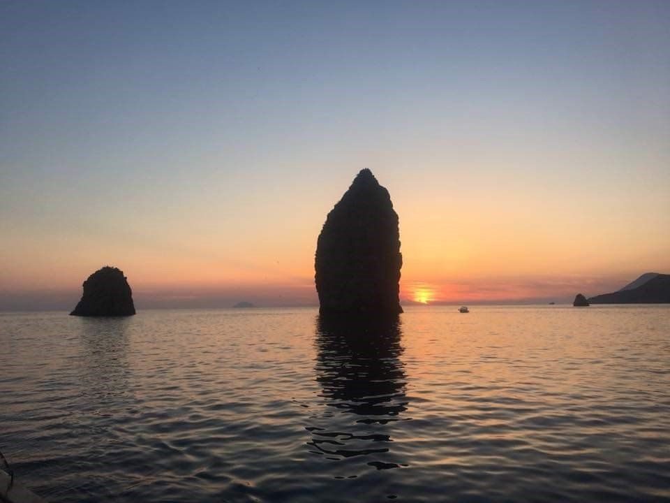 Una grande roccia in mezzo all'oceano al tramonto