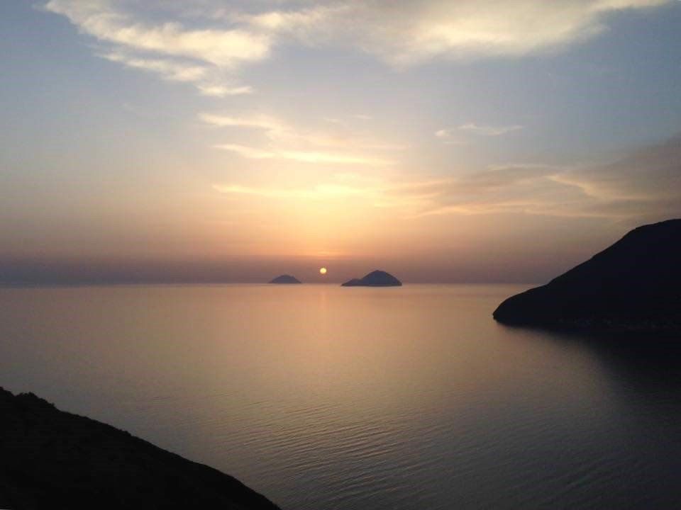 Un tramonto su uno specchio d'acqua con le montagne sullo sfondo