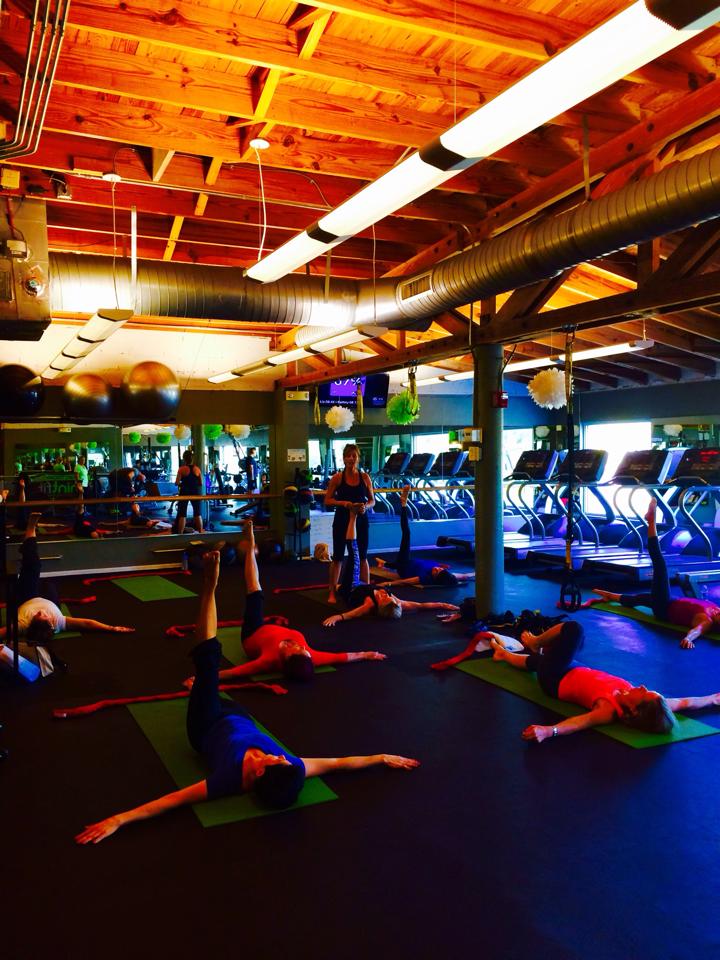 A group of people are doing yoga in a gym.