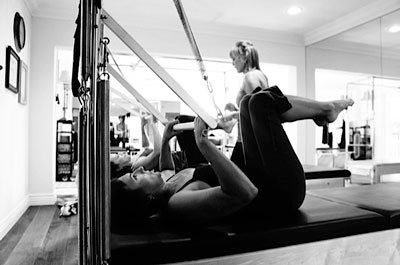 A woman is laying on a pilates machine in a gym.