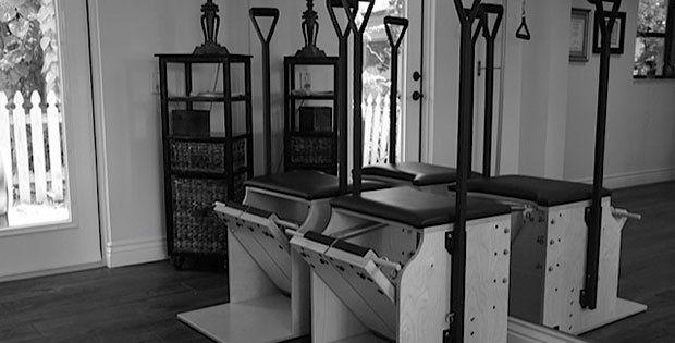 A black and white photo of a pilates machine in a room.