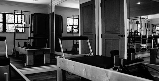 A black and white photo of a pilates studio with a pilates machine.