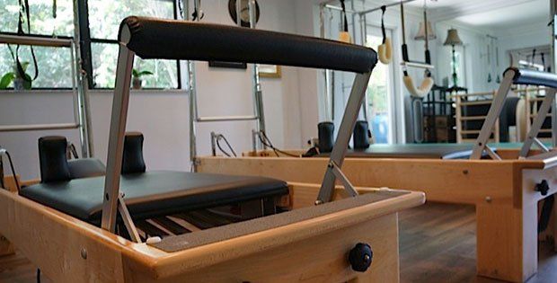 A row of wooden pilates tables in a gym.