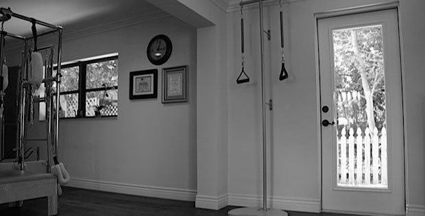 A black and white photo of a room with a pilates machine and a door.