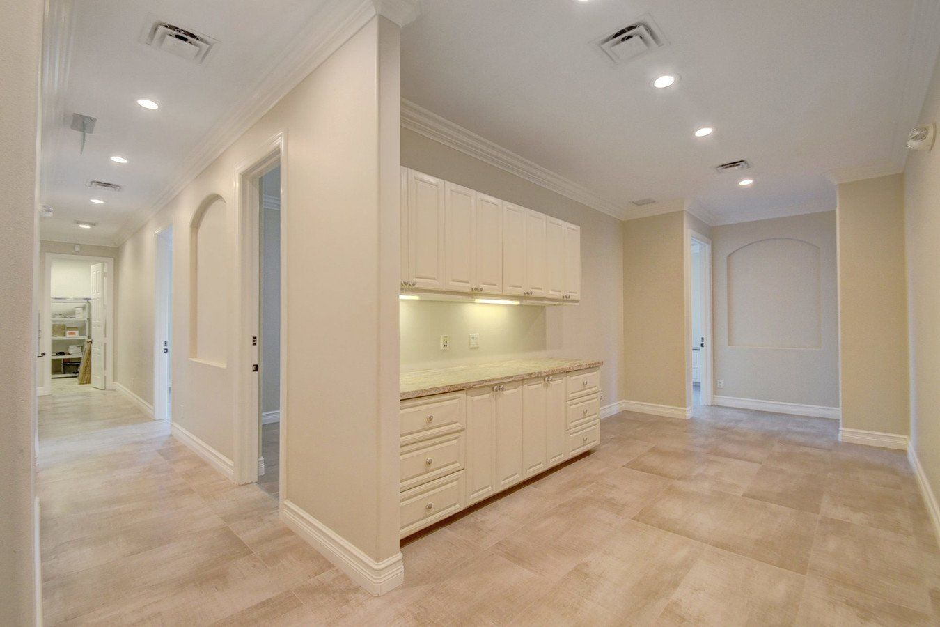 An empty room with white cabinets and a tiled floor.
