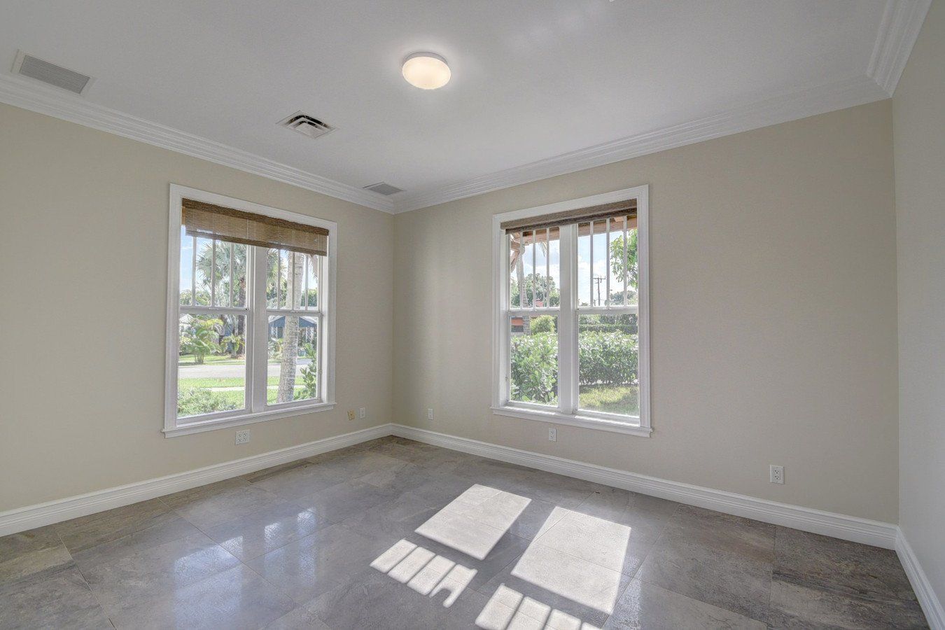 An empty room with two windows and a ceiling light.