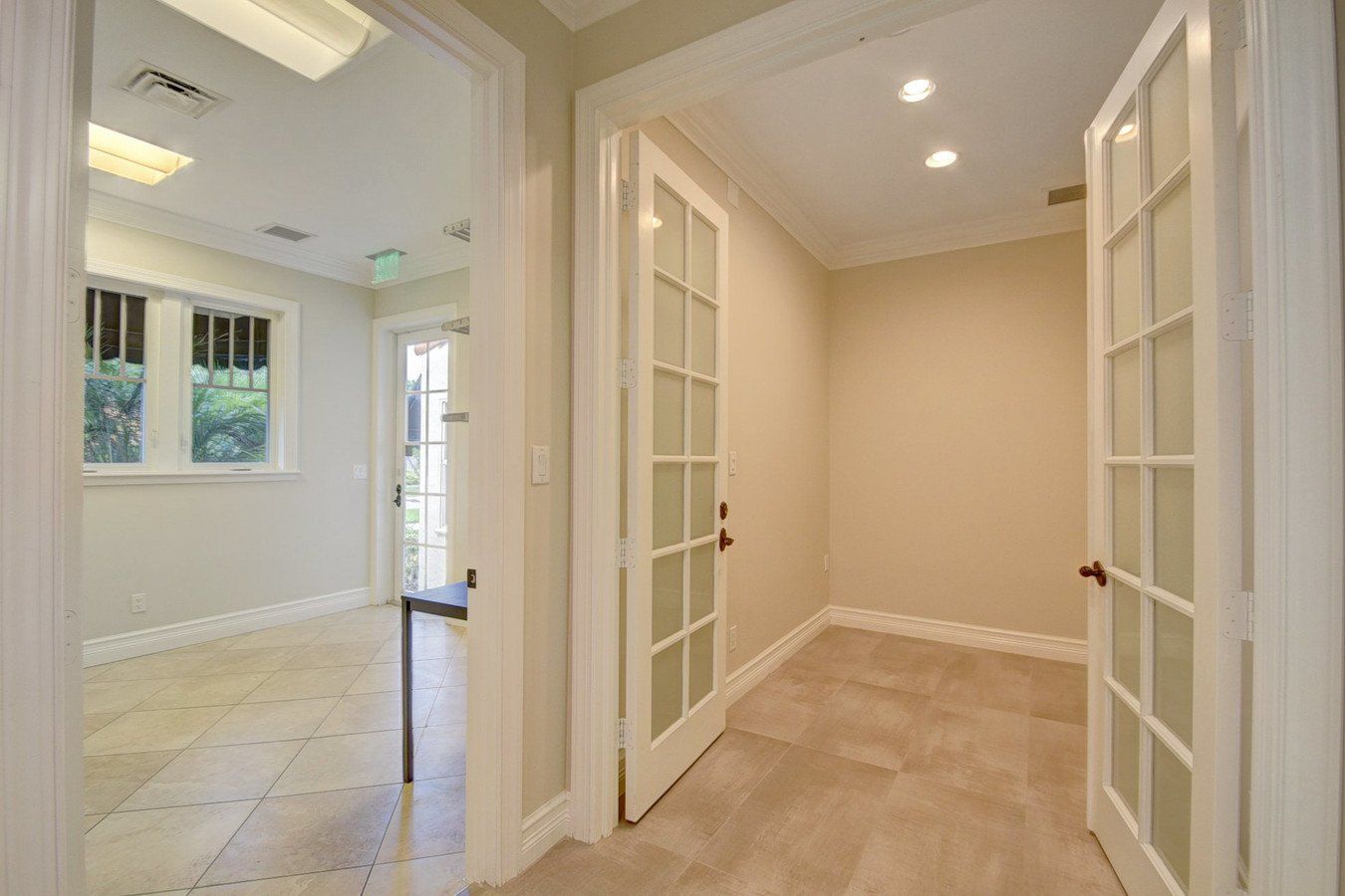 A hallway with french doors leading to an empty room.