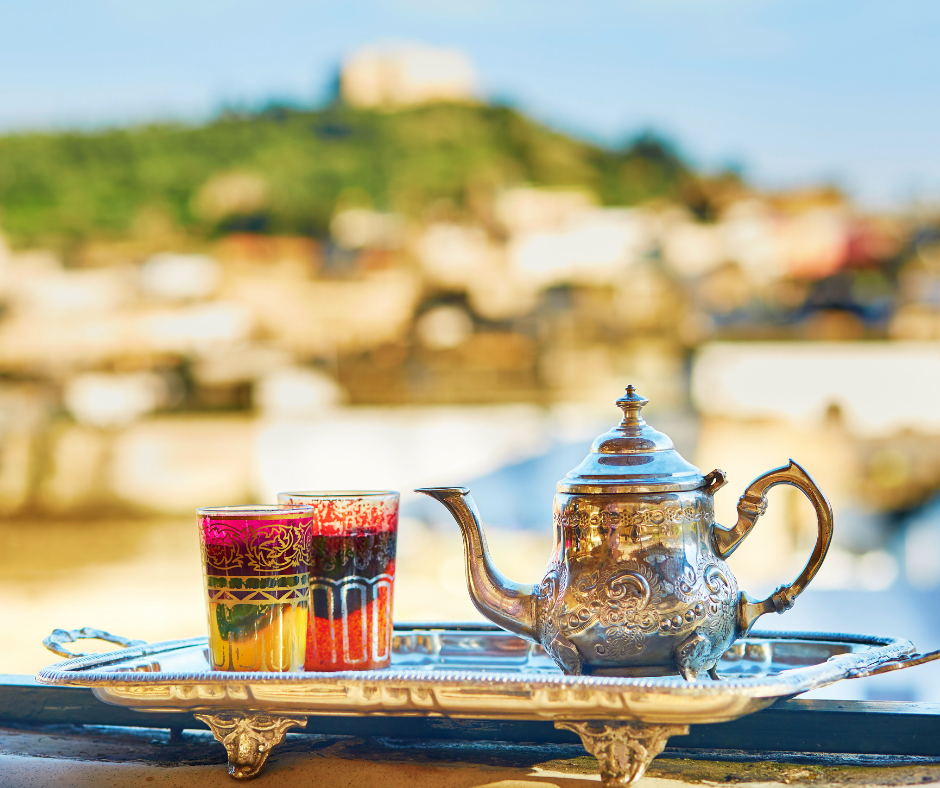 A teapot and two glasses are on a silver tray.