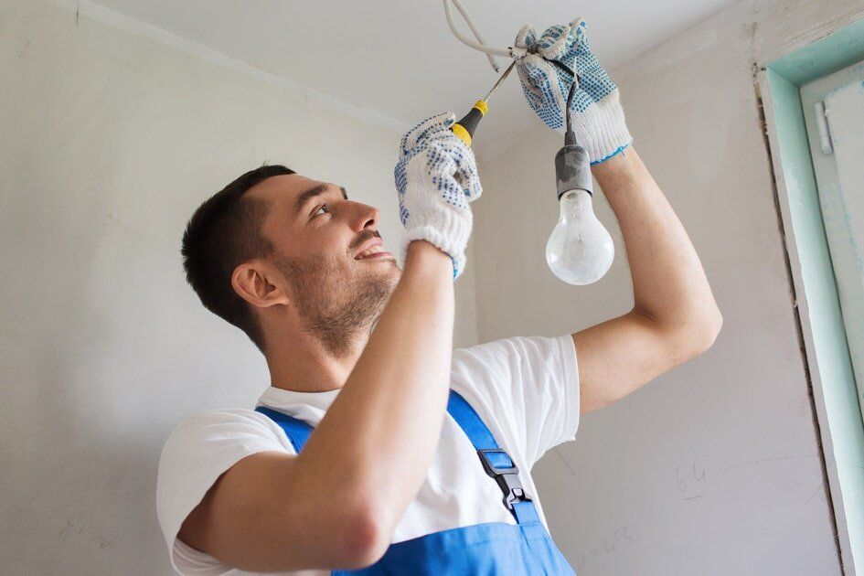 Man Installing Light Bulb — Electrical Services in Jensen, QLD