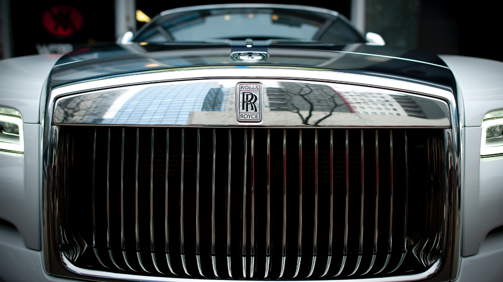 Front view of a white Rolls-Royce coupe Dawn with a  wrapped chrome grille and hood with the Rolls-Royce emblem. 