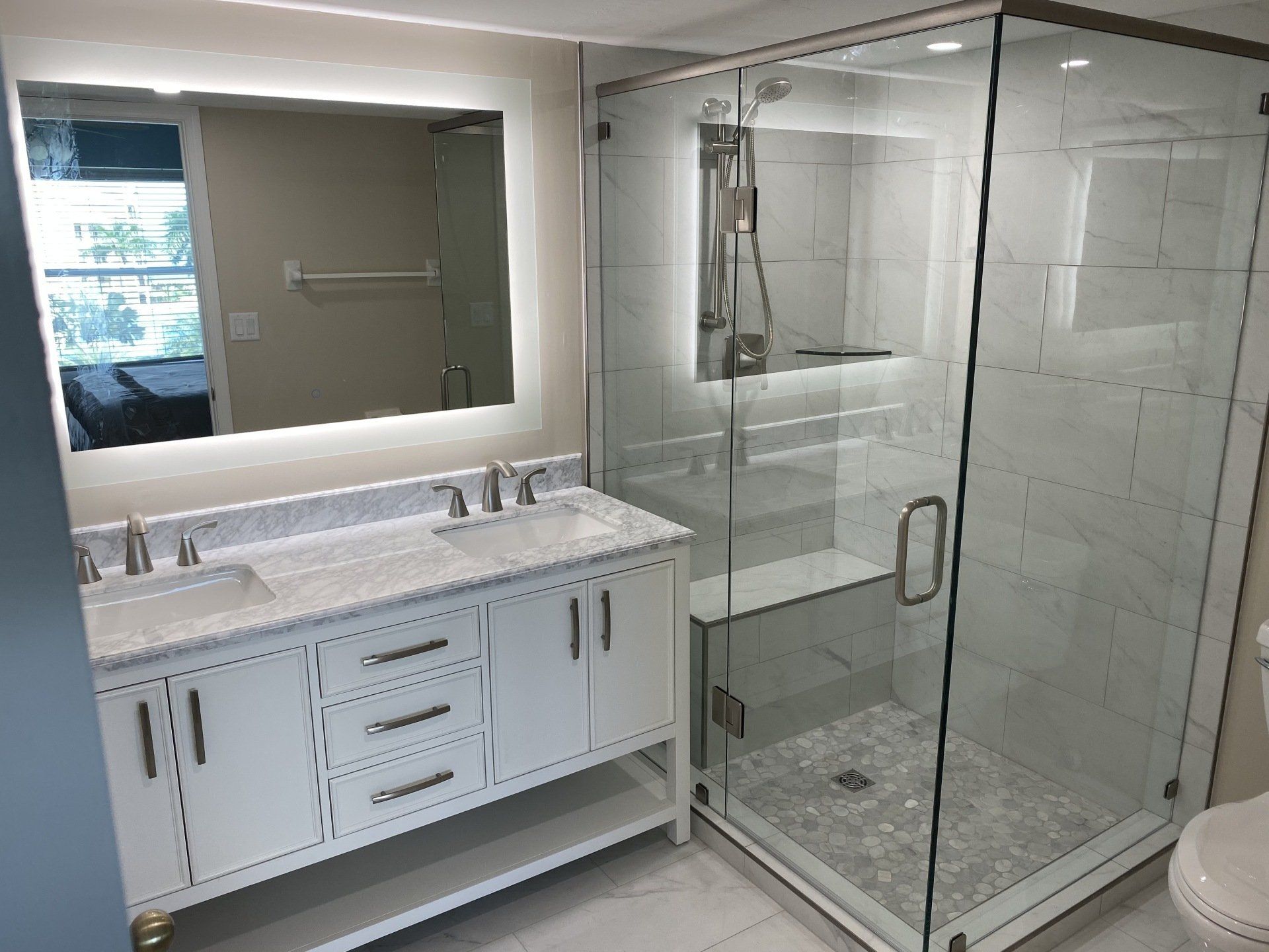 A bathroom with a sink , toilet , shower and mirror.