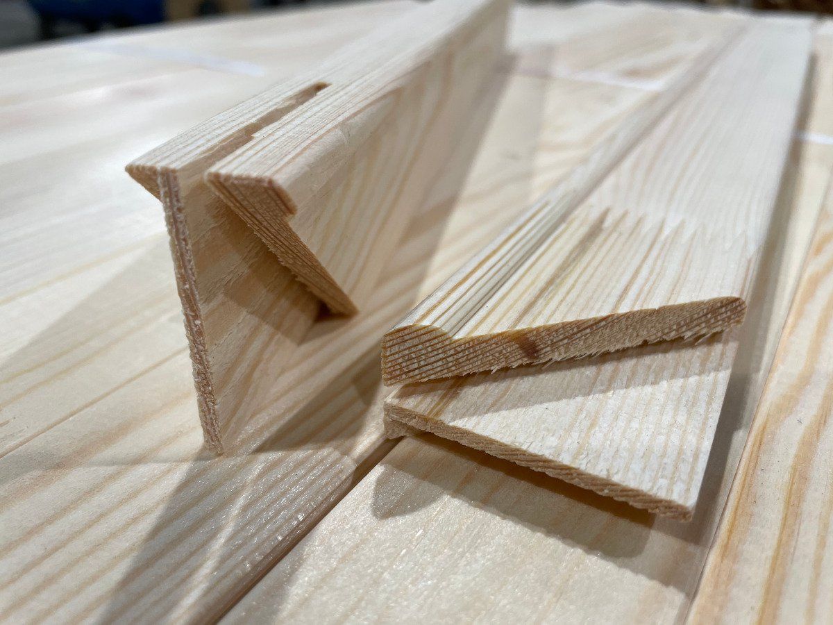 Close-up of two wooden corner joints with triangular braces on a light wood surface