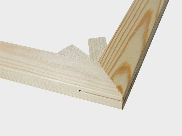 Close-up of two light pine boards joined at a mitered corner with a reinforcing strip.