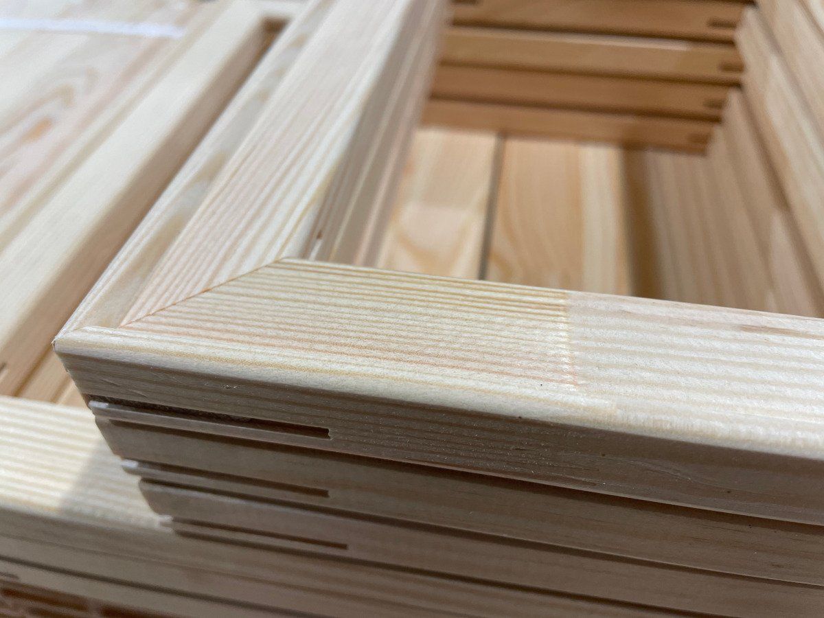Close-up of stacked unfinished wooden slats in a pale wood frame