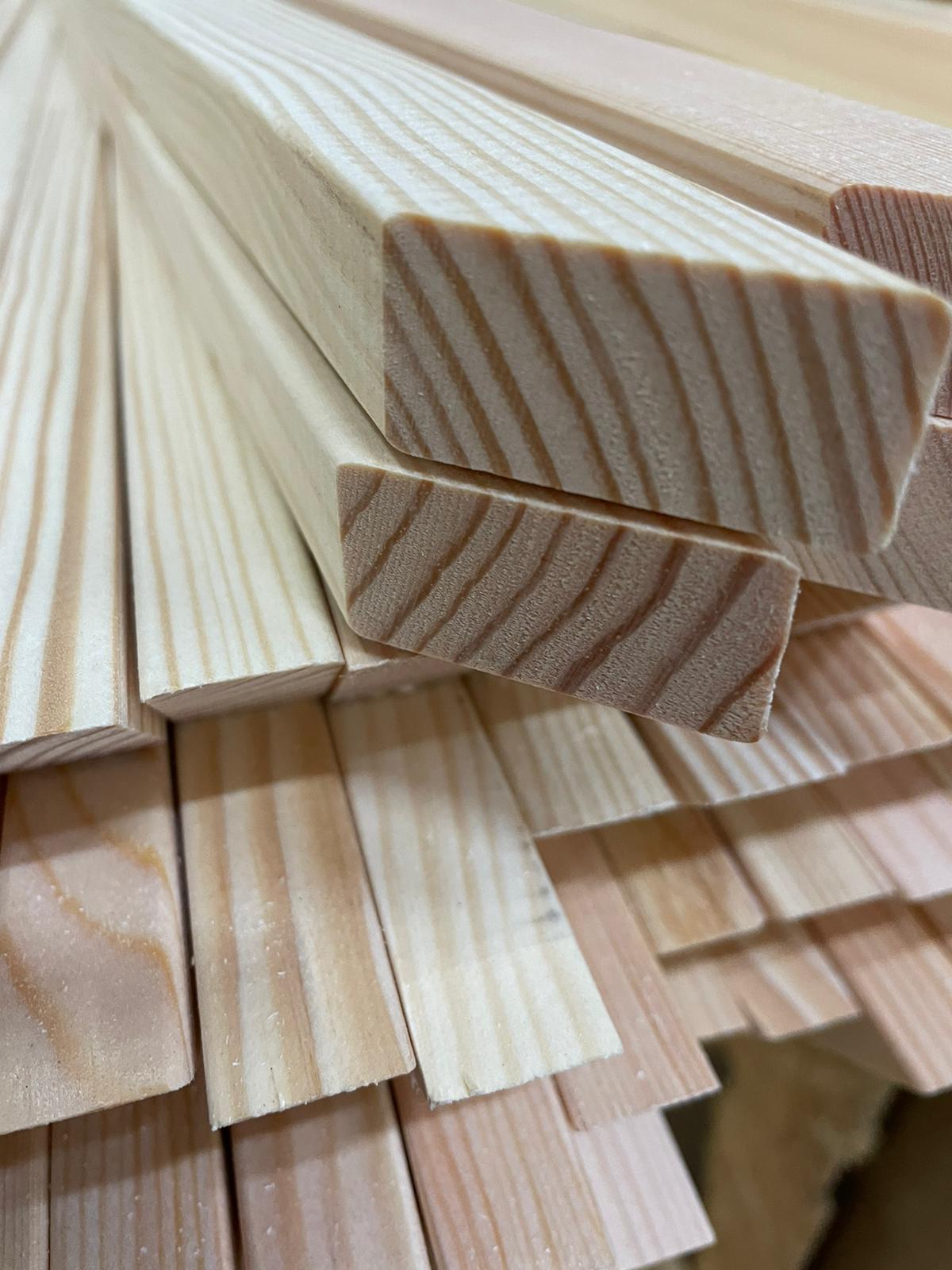 Stacked light-colored wooden boards with visible grain and cut ends