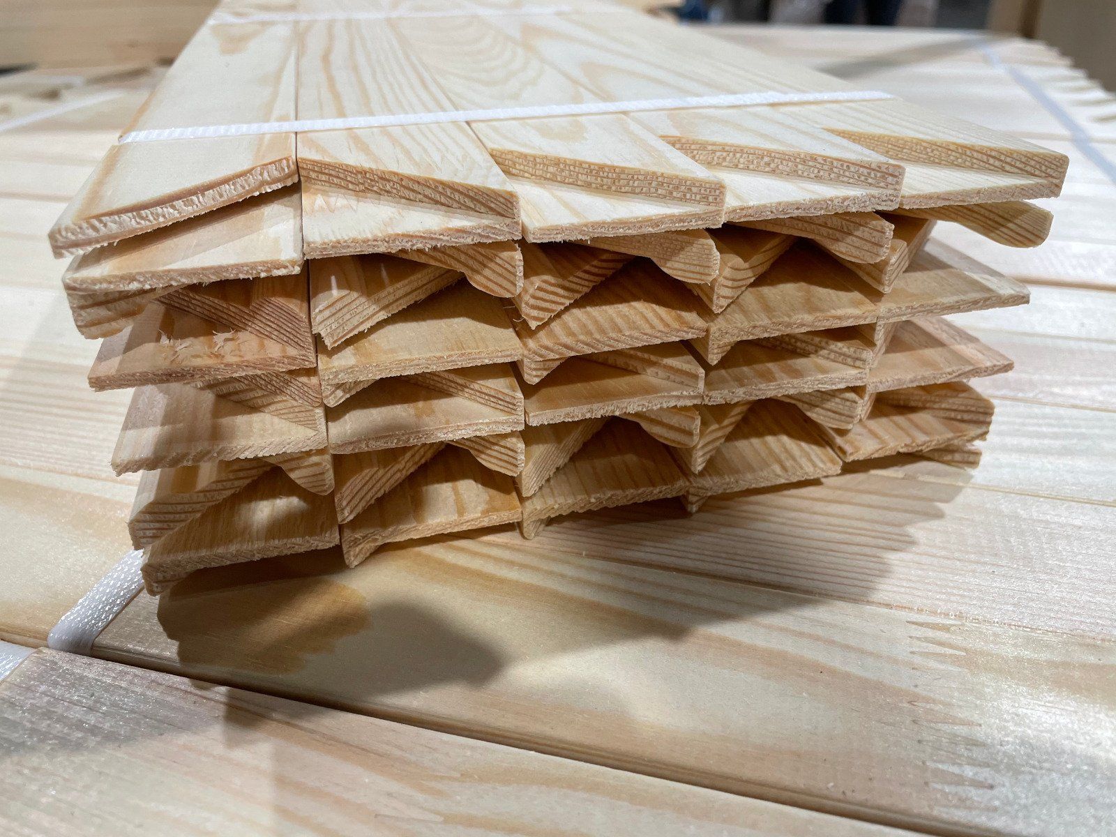 Stack of light wood planks with rough edges on a wooden surface